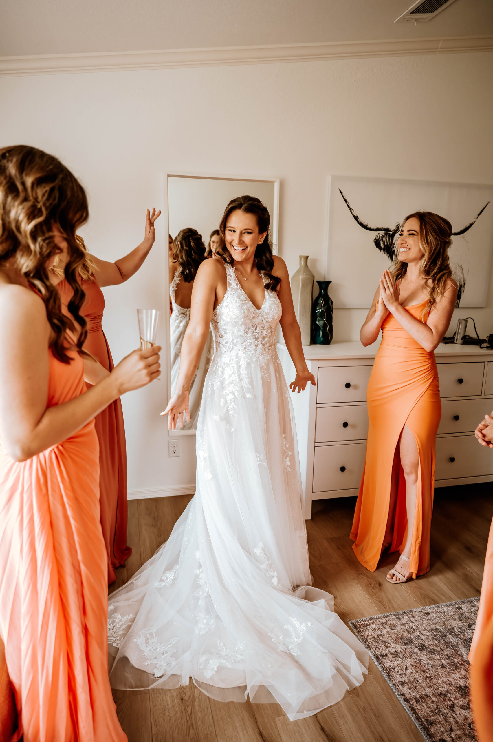 a bride showing off her dress to her bridesmaids